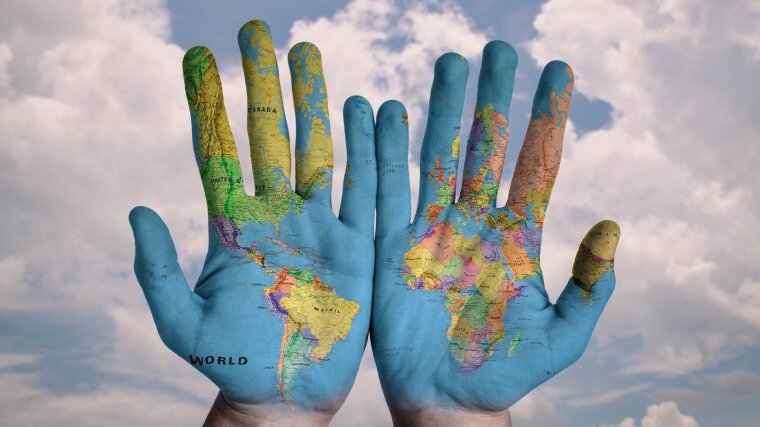 Zwei Hände mit aufgemalter Weltkarte