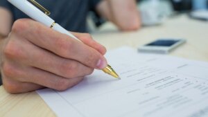 Hand hält Stift vor Blatt